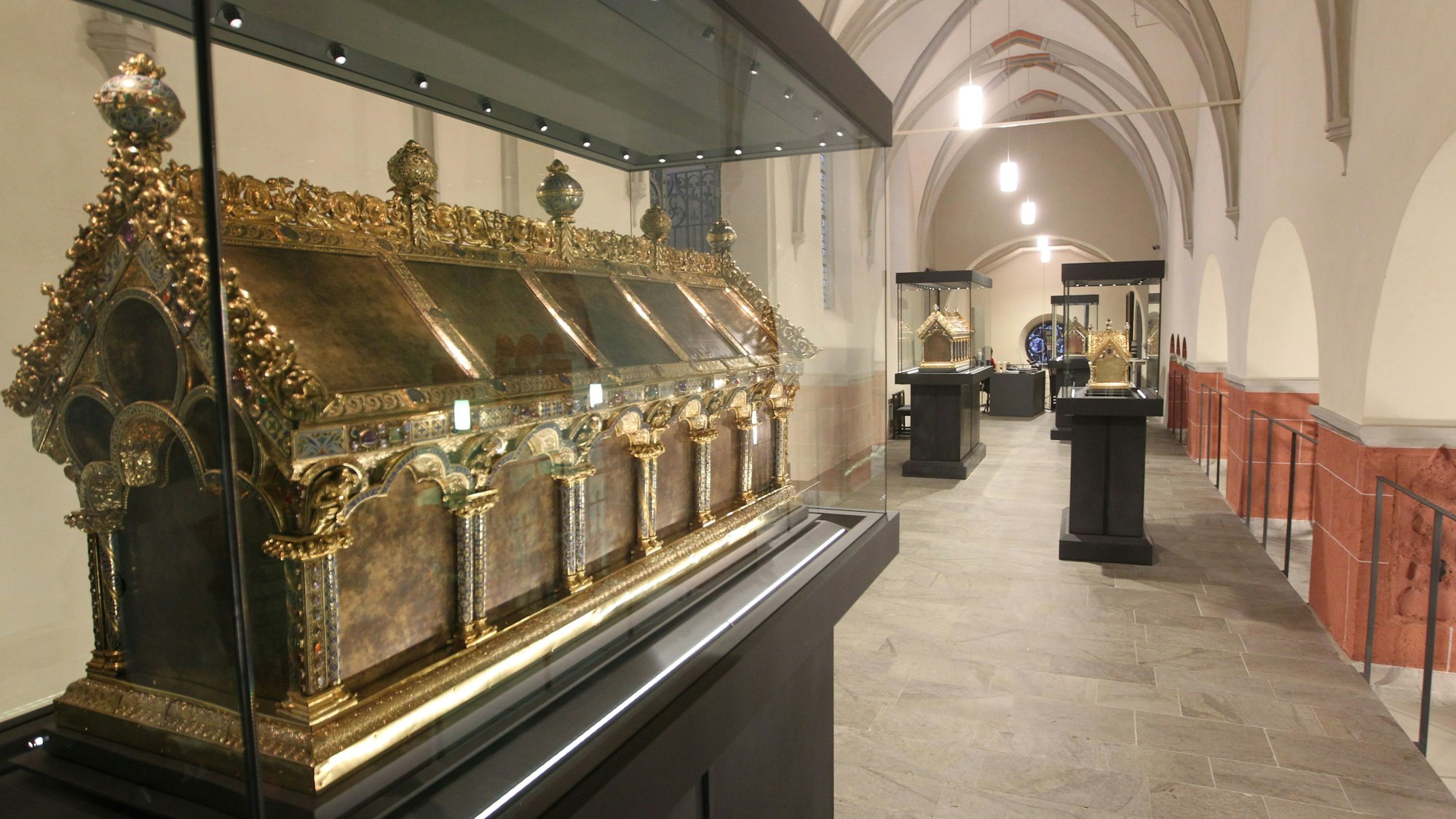 Ein reich verzierter goldener Schrein steht in einer Vitrine, weiter hinten im Kirchenraum sind zwei weitere Vitrinen mit goldenen Schreinen.