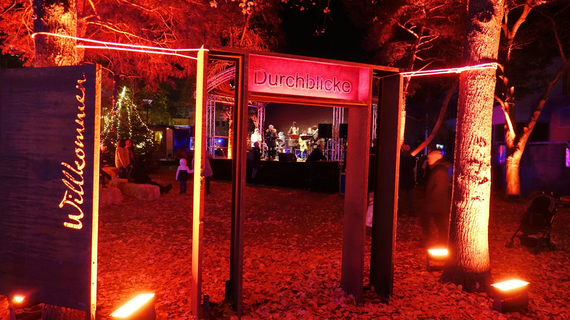 Ein Willkommen in Flammenschrift begrüßt die Besucher im Klosterpark. Ein rotes Tor ermöglicht den Durchblick auf die Eventbühne.