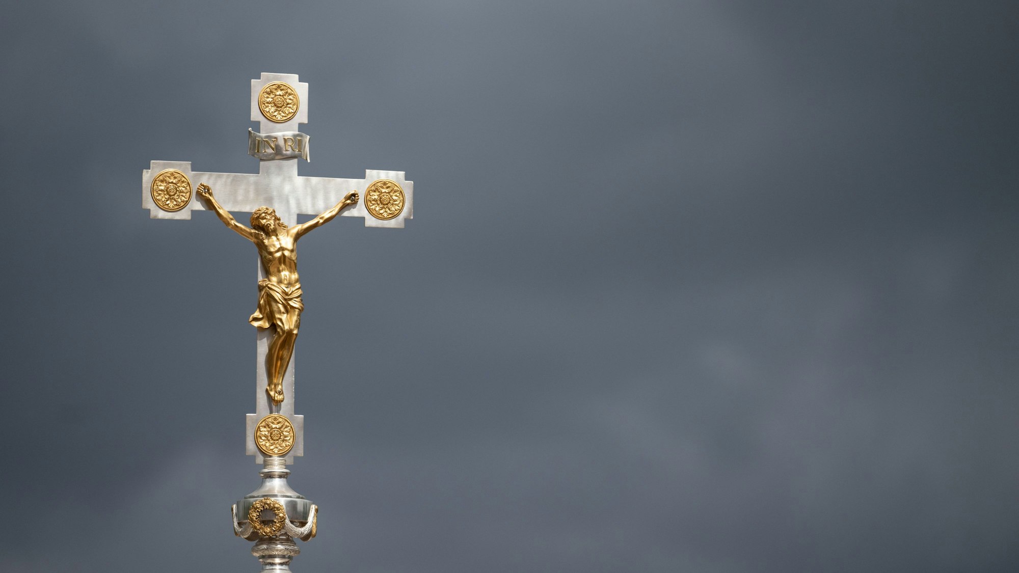 Ein Kruzifix ist beim Schlussgottesdienst des 102. Deutschen Katholikentags vor dunklen Wolken zu sehen.