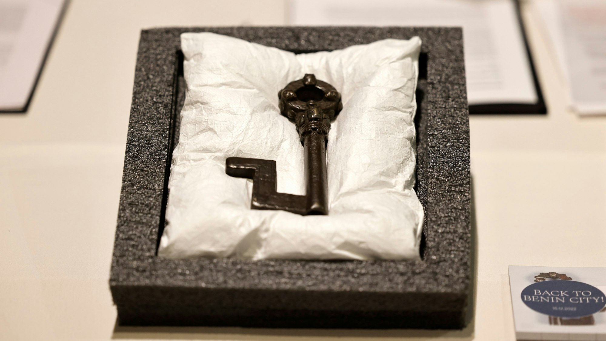 Ein Schlüssel aus Kupfer steht vor der Vertragsunterzeichnung zur Rückführung von Benin-Bronzen aus Köln auf dem Tisch.