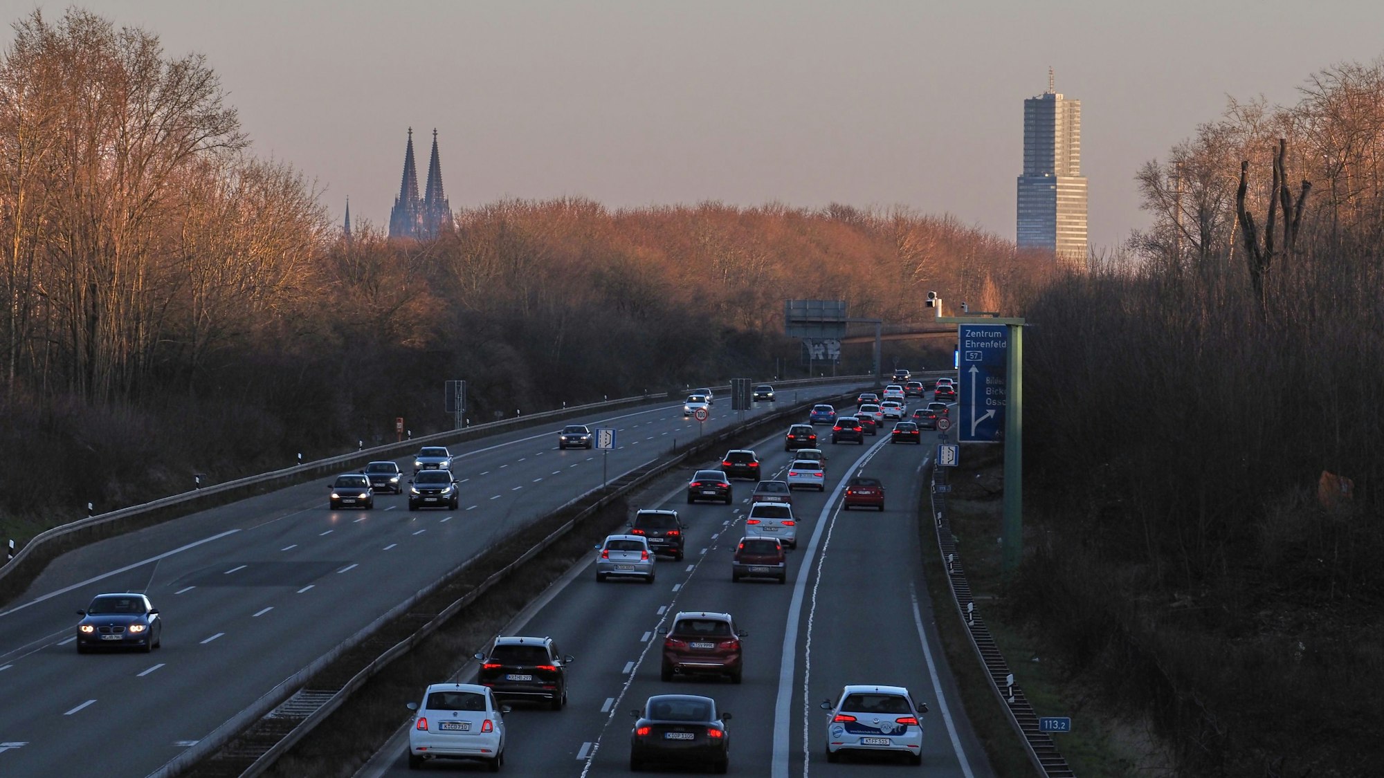 Das Bild zeigt die A57 stadtauswärts, Fahrtrichtung Autobahnkreuz Köln-Nord. Im Hintergrund sind Kölnturm und Dom zu sehen.