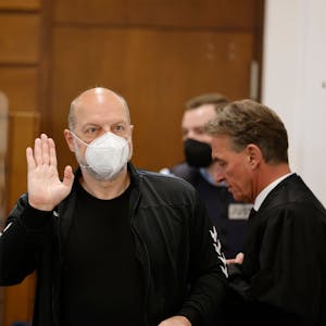 Der Angeklagte Thomas Drach (l) hebt im Kölner Landgericht neben seinem Anwalt Andreas Kerkhof seine Hand zum Gruß.