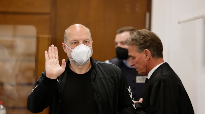 Der Angeklagte Thomas Drach (l) hebt im Kölner Landgericht neben seinem Anwalt Andreas Kerkhof seine Hand zum Gruß.