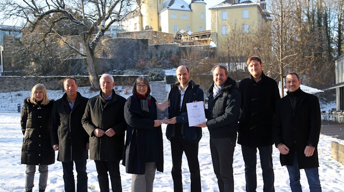Eine Gruppe von Männern und Frauen präsentiert vor Schloss Homburg eine Urkunde.