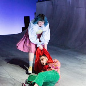 Szene Helges Leben am Schauspiel Köln, ein Mann am Boden wird an seinem roten Schal über die Bühne gezerrt.
