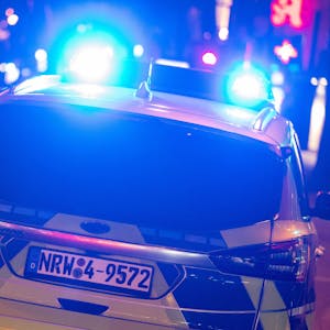 Ein Einsatzfahrzeug der Kölner Polizei von hinten mit Blaulicht bei Nacht.