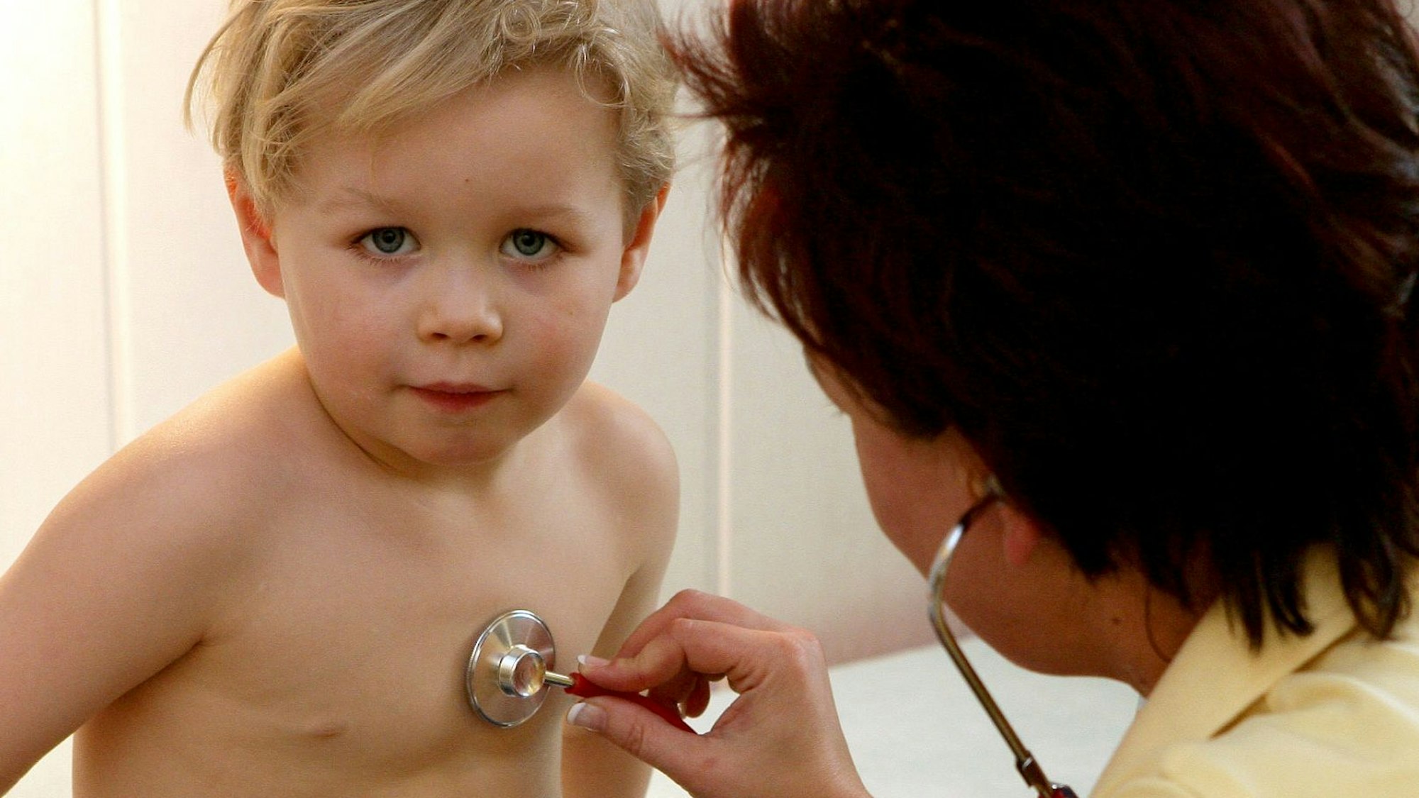 Eine Kinderärztin aus Frankfurt untersucht in ihrer Praxis einen kleinen Jungen mit einem Stethoskop.