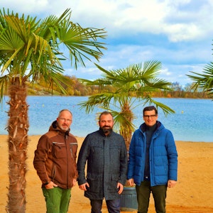 Drei Männer stehen unter Palmen im Seepark Zülpich.