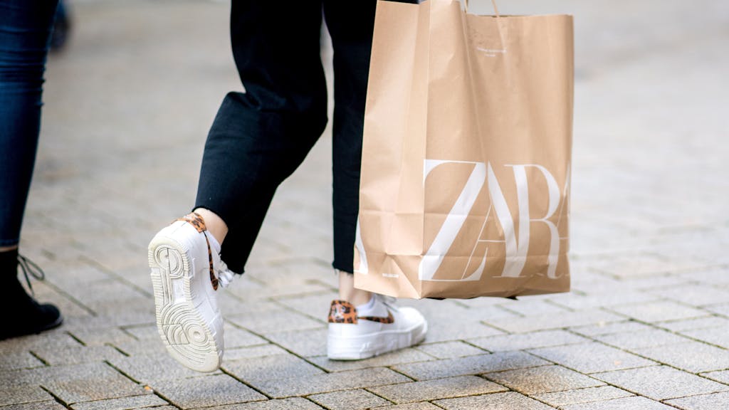 Eine junge Frau geht mit einer Zara-Einkaufstasche durch die Fußgängerzone der Innenstadt. 