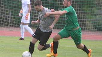 Michael Hermanni (links) vom Siegburger SV 04 führt den Ball und wird von seinem Gegenspieler mit beiden Armen festgehalten.
