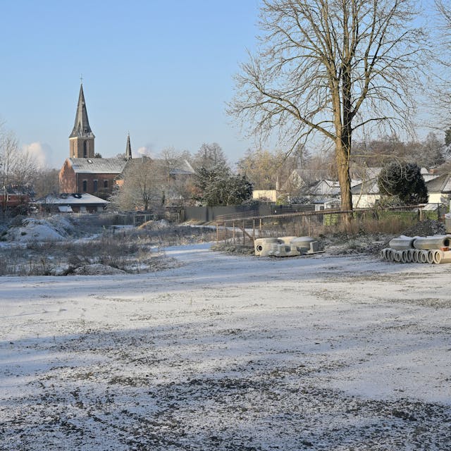 Das Baugrundstück im Schnee, im Hintergrund die Kirche.