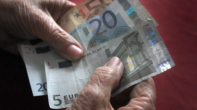 Eine ältere Frau hält verschiedene Euronoten in der Hand.