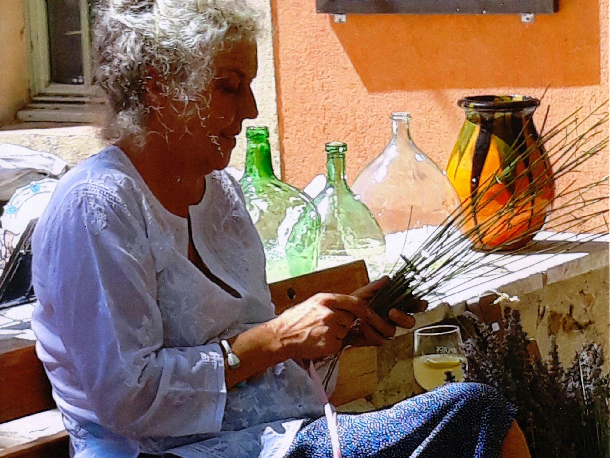 Eine Frau sitzt vor einem Haus und bindet Lavendel.