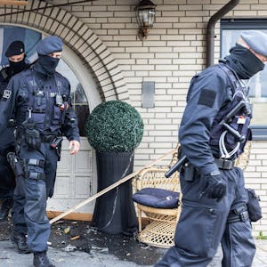 Polizisten verlassen in Leverkusen eine Villa durch eine zerstörte Eingangstür nach Durchsuchungen im Bereich der Clankriminalität.