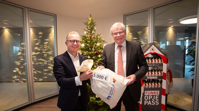 Hilfreich: Jürgen Pütz, Vorstandsvorsitzender der Volksbank Köln Bonn, überreicht Helmut Heinen, Vorsitzender der Altenhilfe, einen symbolisch einen „Sack Geld“.