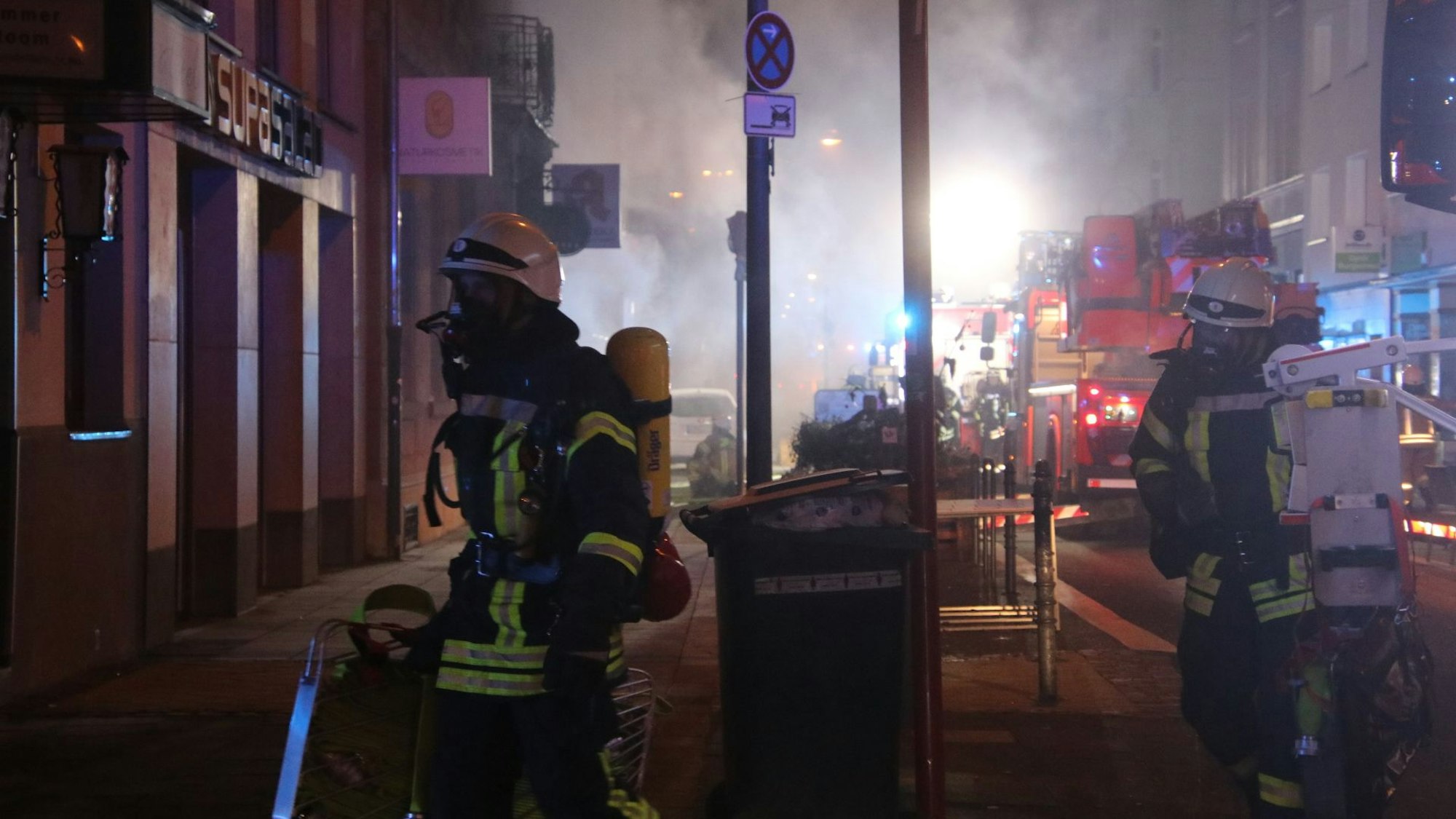 Zwei Feuerwehrleute mit Atemschutzmasken sind beim Brand in einer Apotheke im Einsatz.