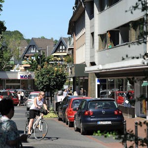 Blick in die Brückenstraße Richtung Kodi mit geparkten Autos, Fußgängern und einer Radfahrerin.