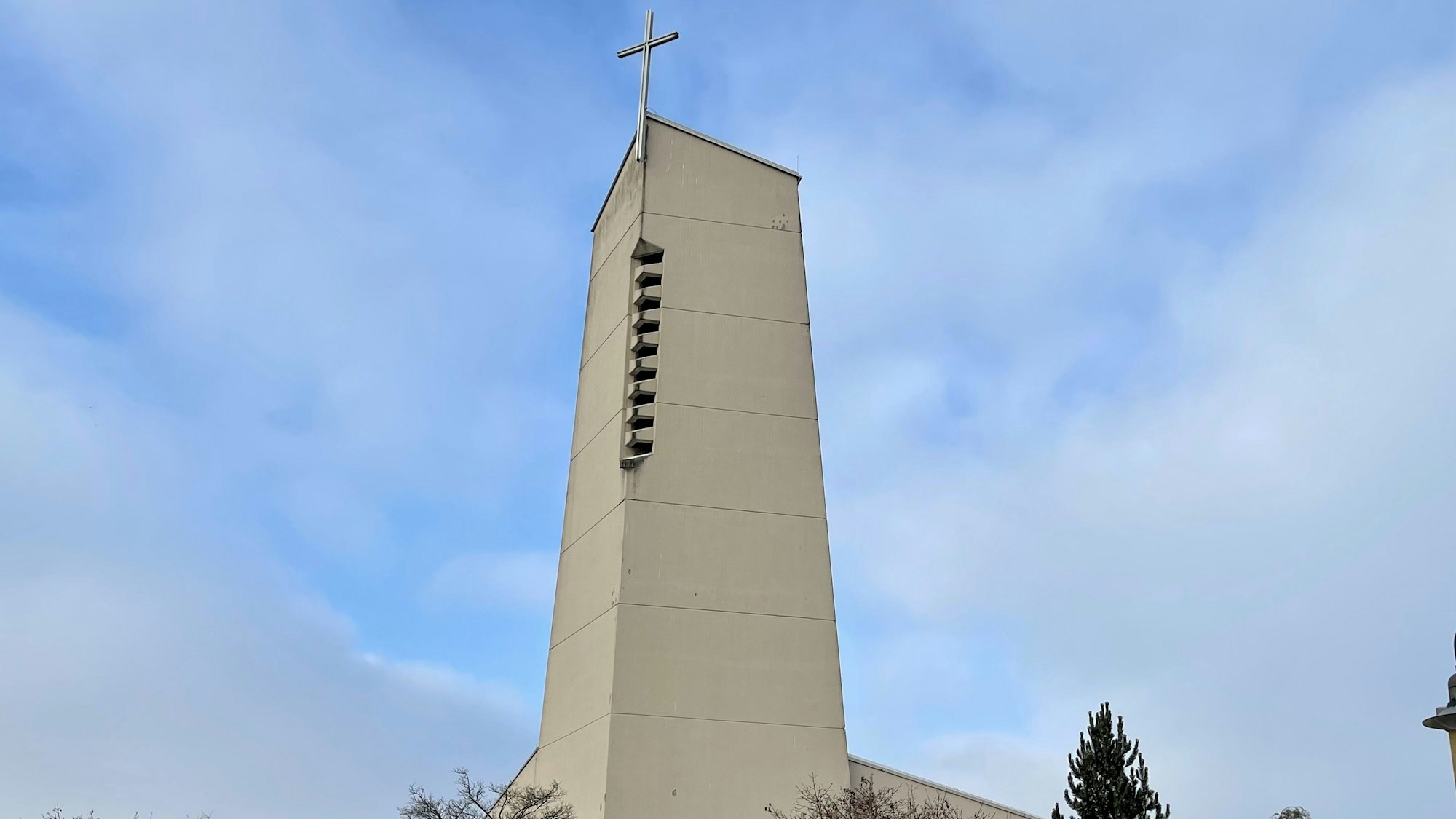 Der Kirchturm der Pfarrgemeinde St. Anna in Sankt Augustin vor blauem Himmel mit weißen Wolken