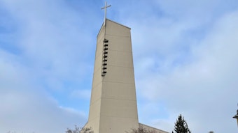 Der Kirchturm der Pfarrgemeinde St. Anna in Sankt Augustin vor blauem Himmel mit weißen Wolken