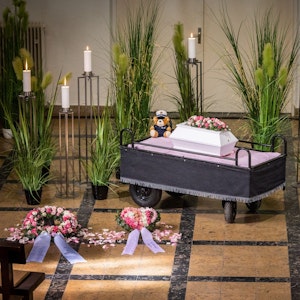 Der winzige weiße Sarg des getöteten Säuglings Rabea mit zwei Blumengestecken ist in der Trauerhalle während der Trauerfeier auf dem Hauptfriedhof Mönchengladbach aufgestellt.