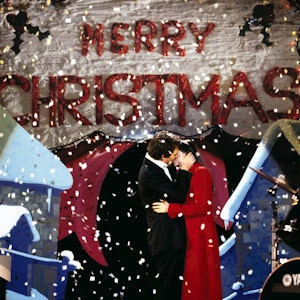 Der englische Premierminister (gespielt von Hugh Grant) küsst seine Angestellte Natalie (gespielt von Martine McCutcheon) auf einer Bühne. Von oben rieselt weißes Konfetti auf die beiden herab.