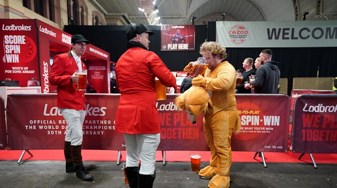 Darts-Fans in Kostümen trinken während des zweiten Tages der Cazoo World Darts Championship im Alexandra Palace Bier.