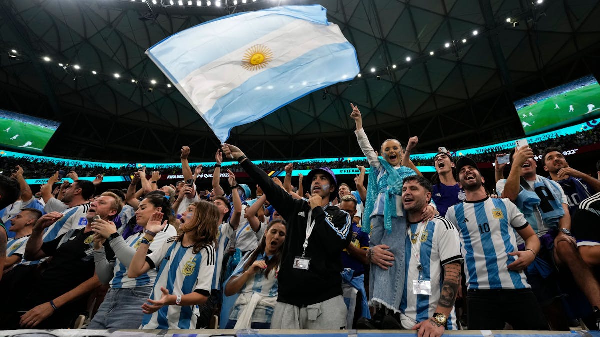 Argentinien-Fans singen bei einem WM-Spiel lautstark und schwenken eine argentinische Flagge.