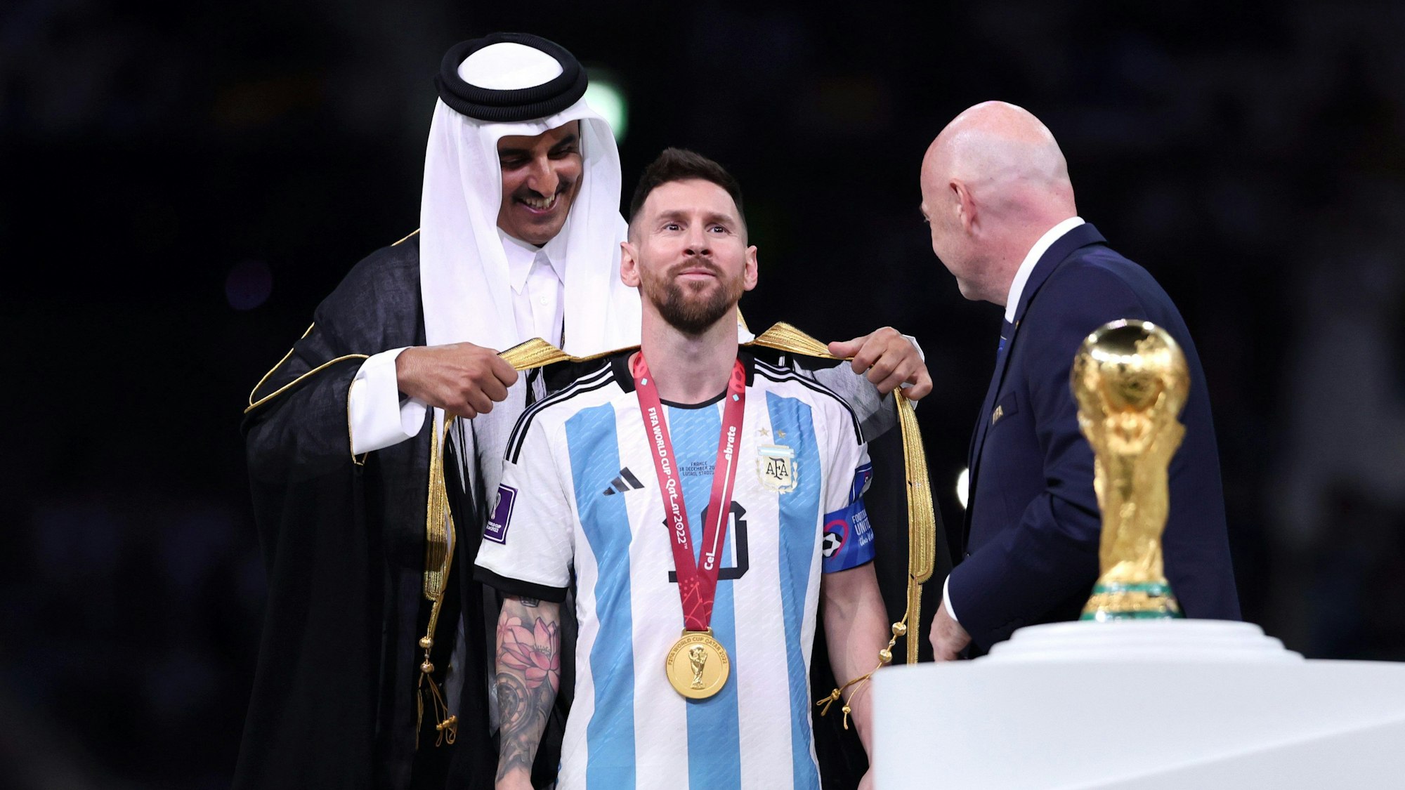 Lionel Messi bekommt erst ein Gewand, dann den WM-Pokal.