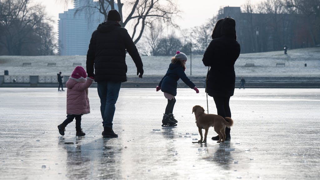 Köln: Eltern spazieren mit ihren Kindern über den zugefrorenen Aachener Weiher.