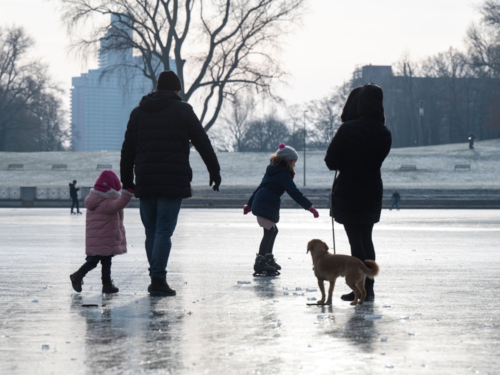 Köln: Eltern spazieren mit ihren Kindern über den zugefrorenen Aachener Weiher.