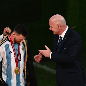Der katarische Emir Emir Tamim bin Hamad Al Than zieht Lionel Messi bei der WM-Siegerehrung einen goldverzierten Umhang über. Fifa-Präsident Gianni Infantino steht daneben.