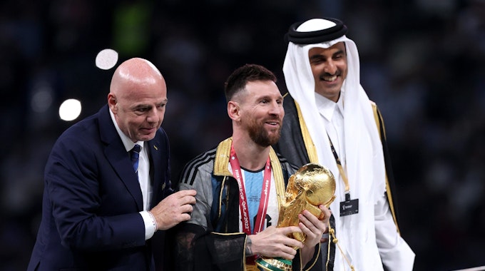 Lionel Messi steht bei der Siegerehrung mit dem WM-Pokal neben Fifa-Präsident Gianni Infantino und Katars Emir Tamim bin Hamad Al Thani.