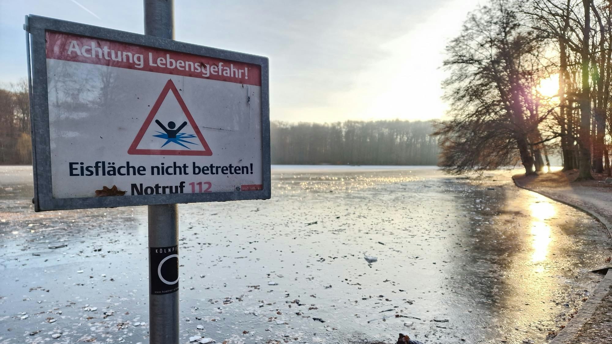 Ein Warnschild am Adenauer Weiher weist auf die Gefahr beim Betreten der Eisfläche hin.
