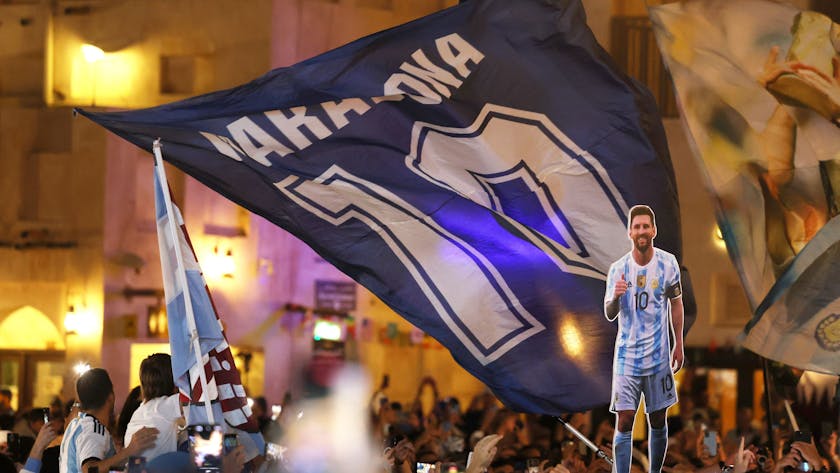 Fans der argentinischen Nationalmannschaft haben sich am Souk Waqif in Doha versammelt. Eine riesige Maradona-Flagge mit der Zehn des Superstars weht, davor ist eine Pappfigur des aktuellen Kapitäns der Argentinier zu sehen, Lionel Messi.&nbsp;