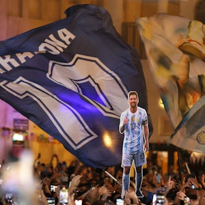 Fans der argentinischen Nationalmannschaft haben sich am Souk Waqif in Doha versammelt. Eine riesige Maradona-Flagge mit der Zehn des Superstars weht, davor ist eine Pappfigur des aktuellen Kapitäns der Argentinier zu sehen, Lionel Messi.