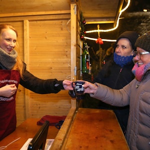 Unsere Autorin Lilian Kraft (l.) reicht eine Tasse Glühwein über den Tresen. Sie half am Samstag auf dem Bielsteiner Weihnachtsmarkt in der Glühweinbude des Heimatvereins mit und berichtet hier.