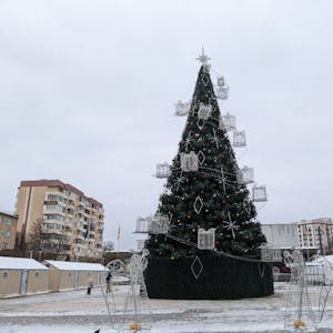 Ein Weihnachtsbaum steht auf einem Platz zwischen Zelten.