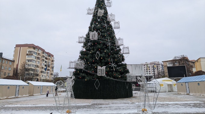 Ein Weihnachtsbaum steht auf einem Platz zwischen Zelten.