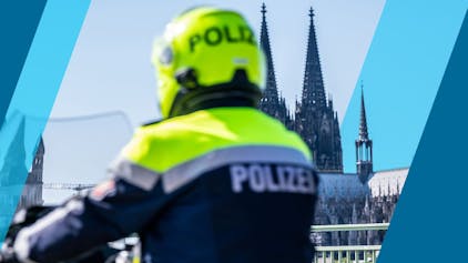 Ein Kölner Polizist auf dem Motorrad, im Hintergrund der Dom.