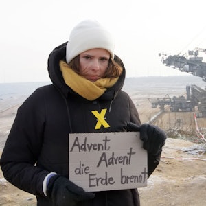Luisa Neubauer hält in Erkelenz-Lützerath ein Protestschild hoch.
