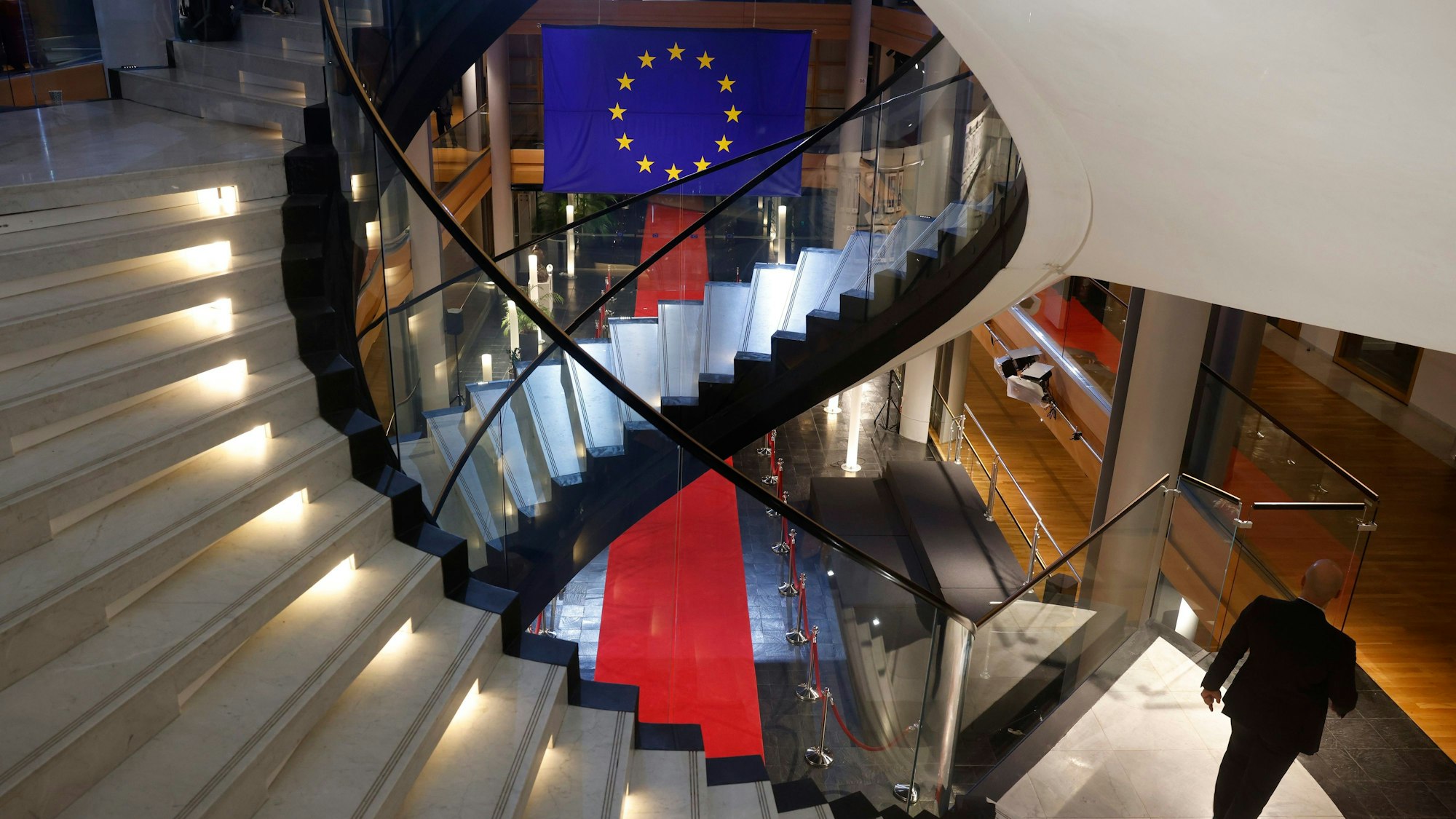 Ein Mann läuft eine Treppe im EU-Parlament in Straßburg herunter. Zu sehen ist zudem die Flagge der Europäischen Union. (Symbolbild)