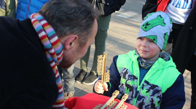 Der kleine Meilo steht vor dem Oberbürgermeister, der ihm auf dem Naturgut Ophoven gerade ein Goldenes Thermometer überreicht hat.