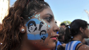 Eine Frau hat ein Tattoo auf der Wange, auf dem Messi und Maradona zu sehen sind.
