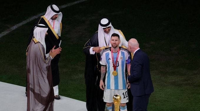 Katars Emir Sheikh Tamim bin Hamad al-Thani stülpt Lionel Messi das arabische Gewand über.&nbsp;