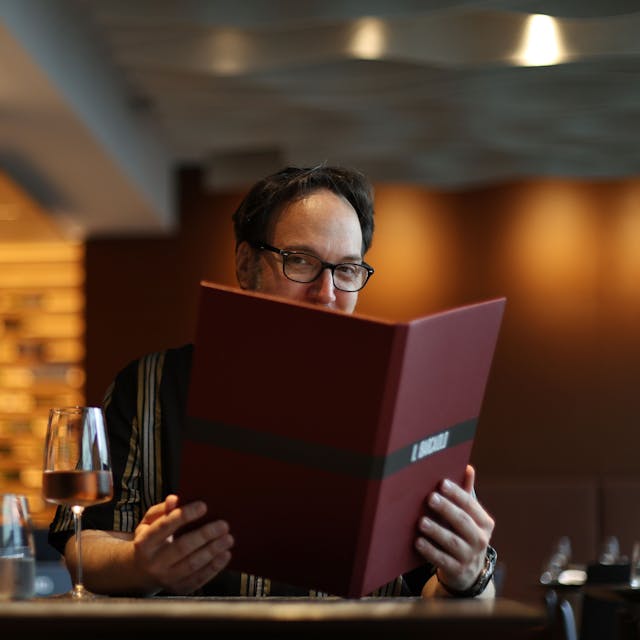 Mann mit Brille schaut in eine Speisekarte
