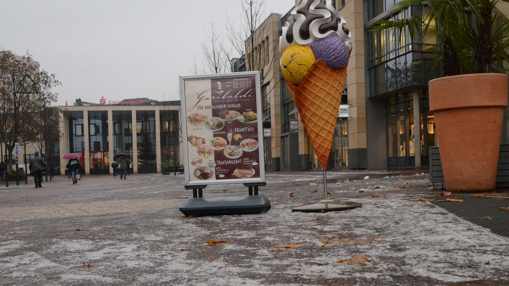 Die Straße in der Siegburger Innenstadt ist vereist. Ein Café hat eine Speisekarte und ein Eis vor die Türe gestellt.
