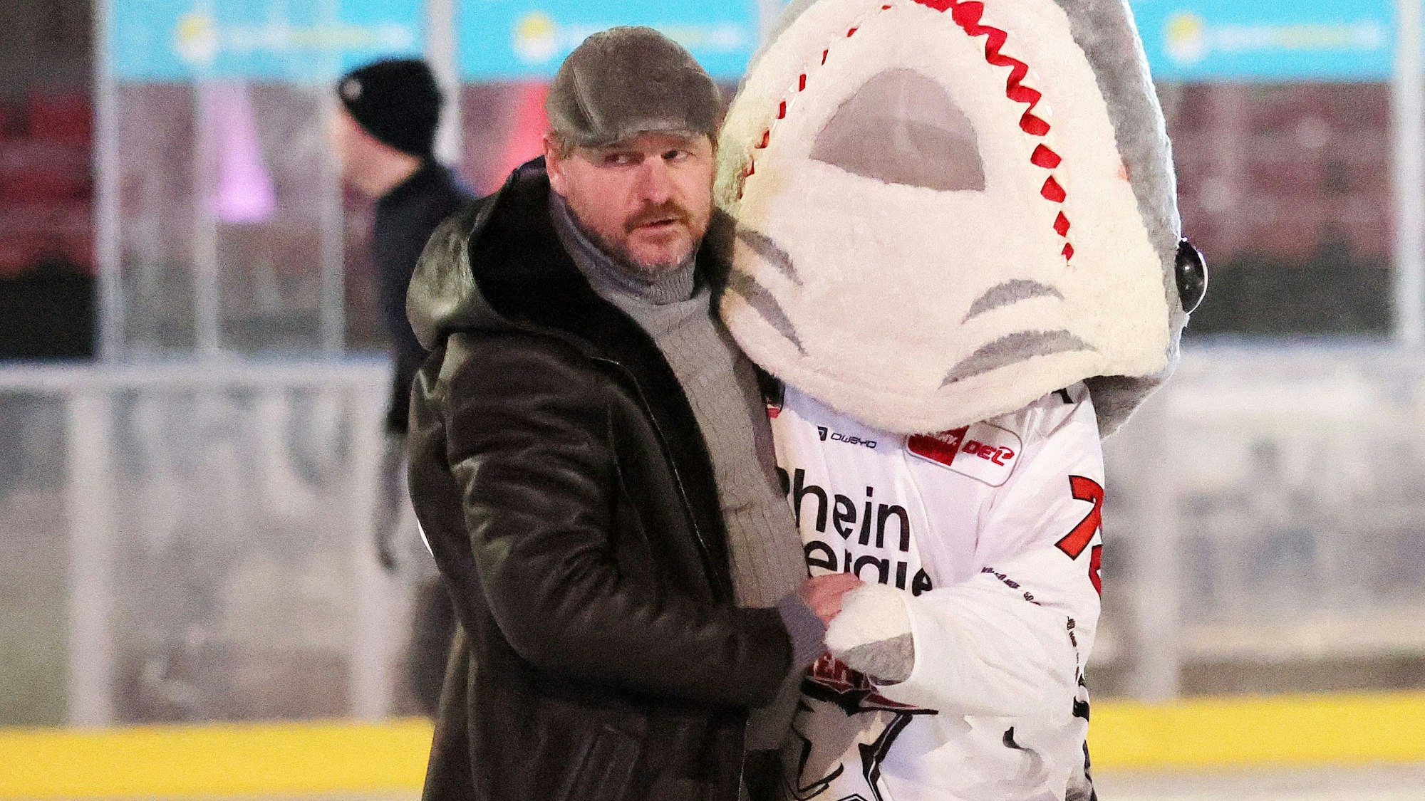1. FC Köln-Coach Steffen Baumgart tanzt mit Haie-Maskottchen Sharky auf dem Eis.