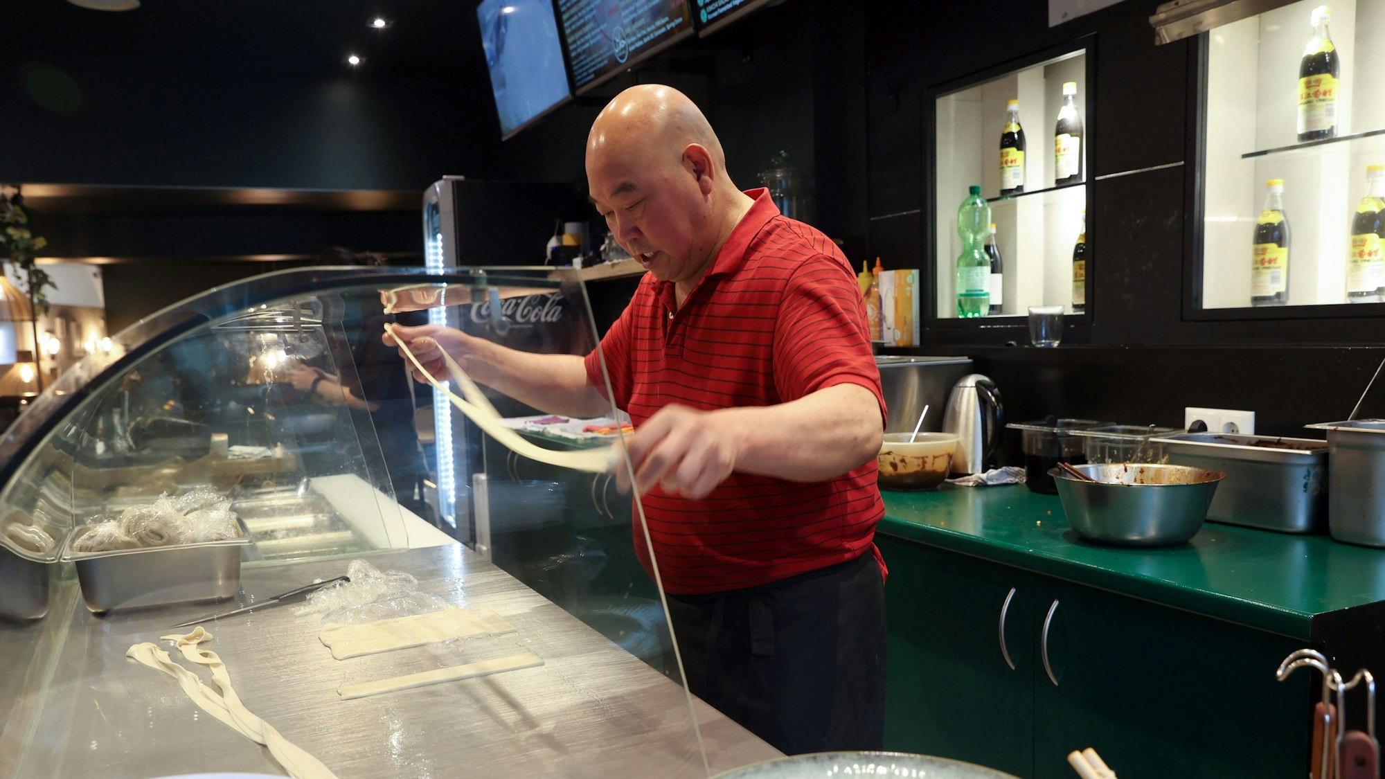 Koch im Kölner Restaurant Noodle Fan zieht Weizenmehlteig auseinander, um Nudeln herzustellen.