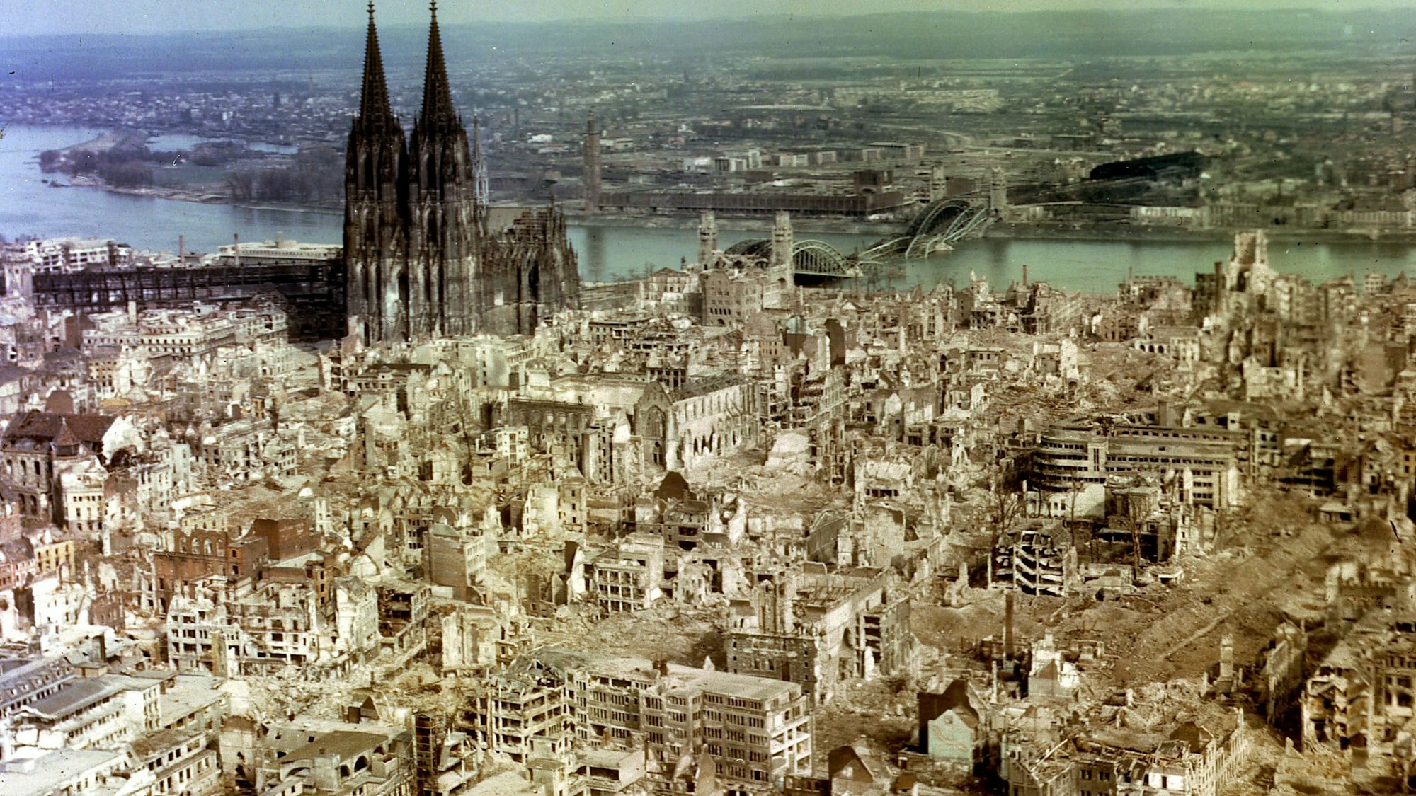Die Luftaufnahme aus dem Jahr 1945 zeigt die im Zweiten Weltkrieg durch alliierte Bombenangriffe zerstörte Innenstadt von Köln. Links der fast unbeschädigte Kölner Dom.