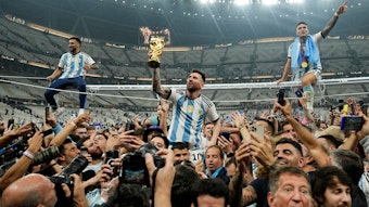 Lionel Messi wird auf Händen getragen und reckt den WM-Pokal in die Höhe